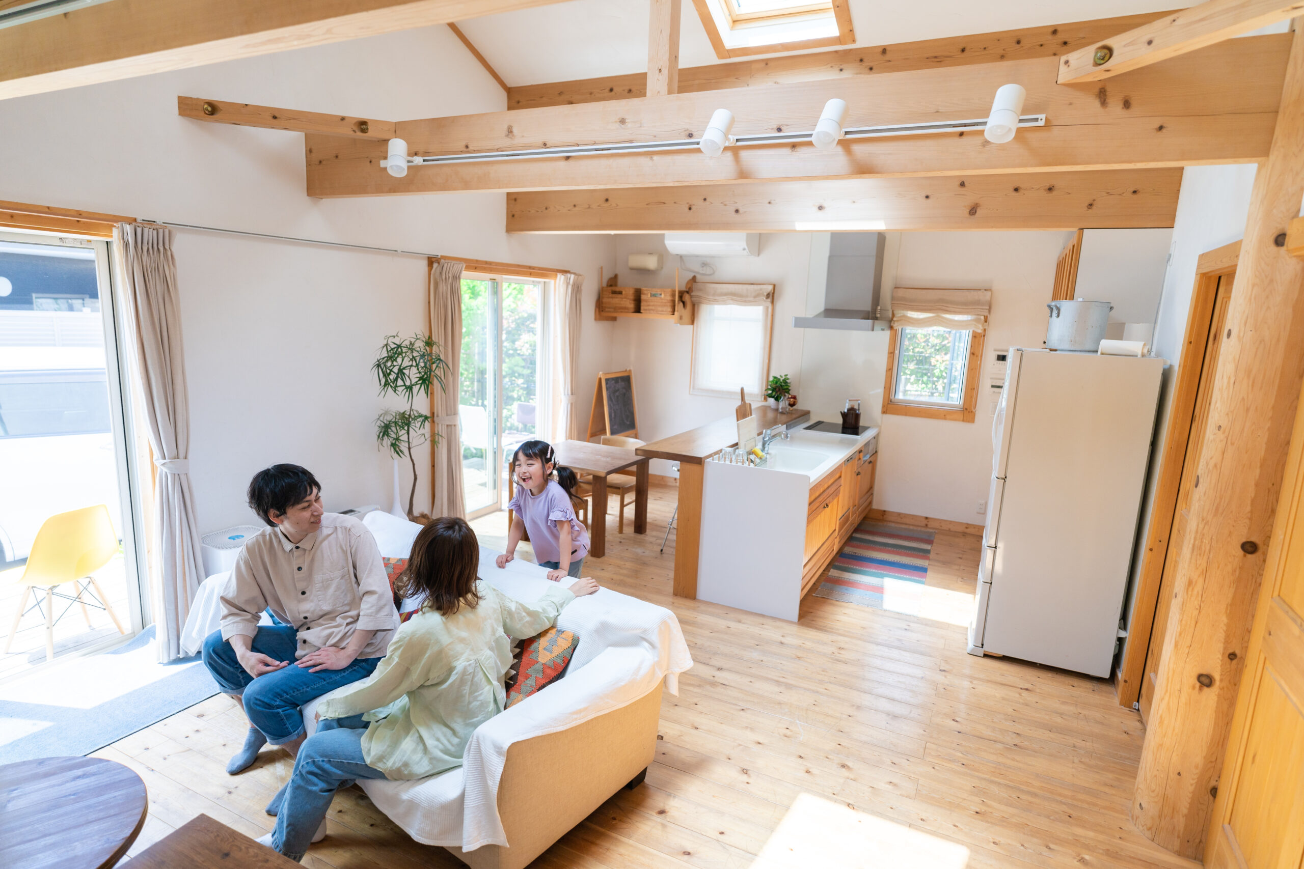 梁の見える勾配天井のLDKでくつろぐご家族（デモ）